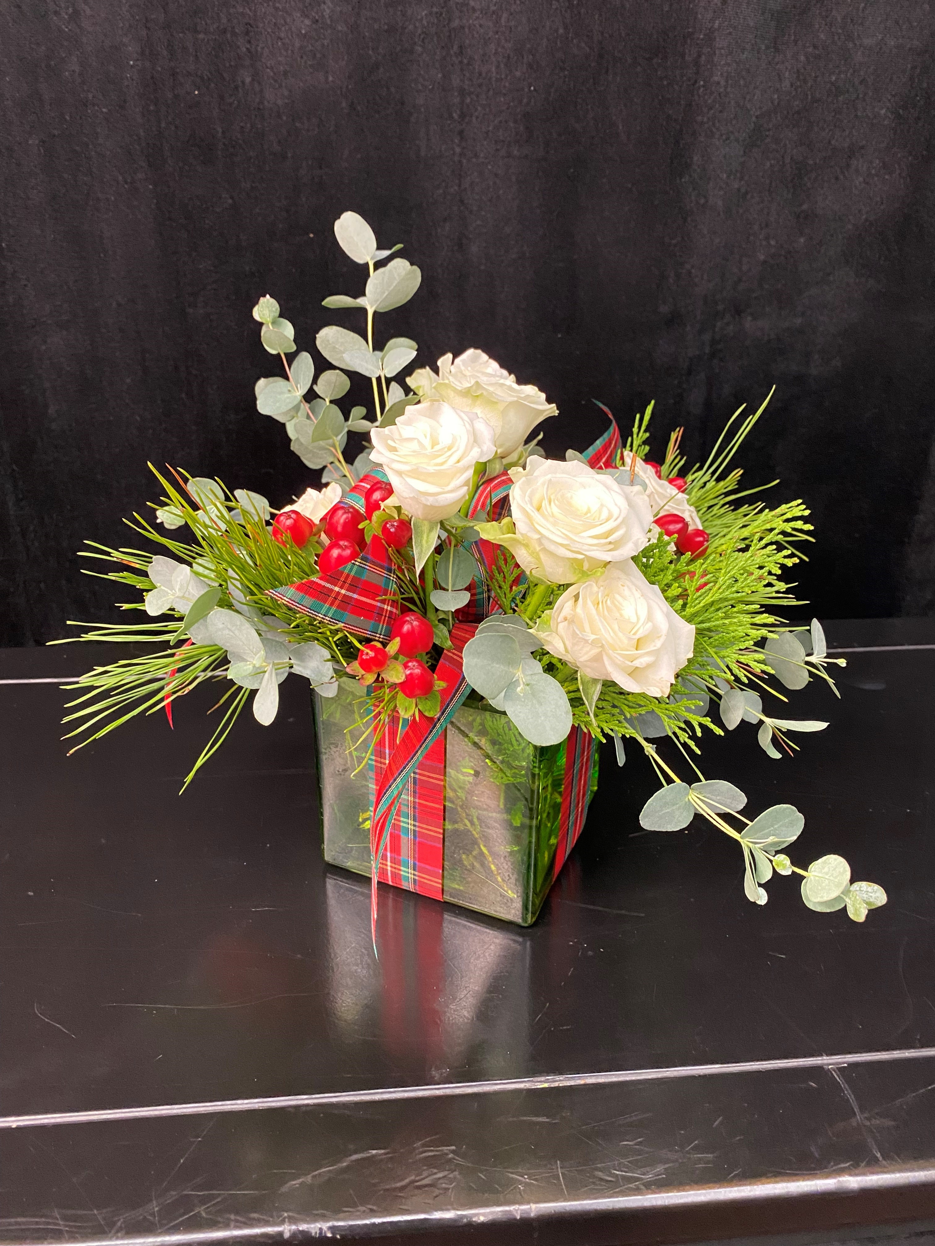 A floral arrangement in a glass cube with ribbon.