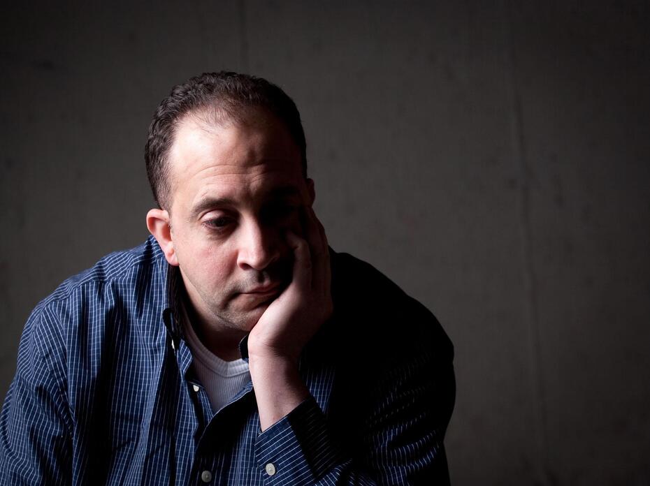 A man sits with his chin proped on his hand