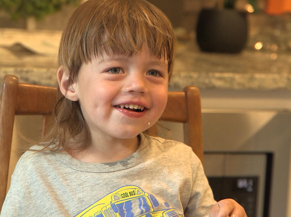 A child smiles at the dining table.