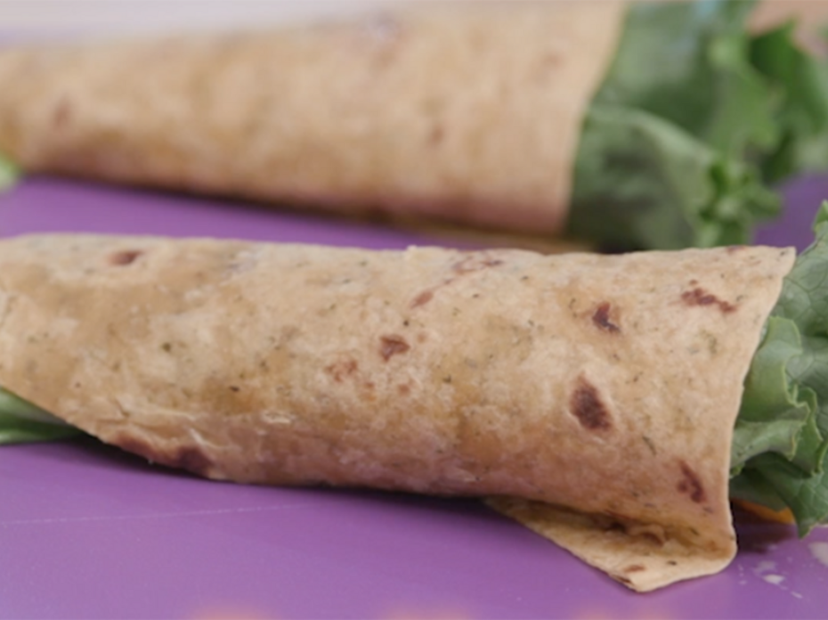  Green lettuce and cooked chicken wrapped in a wheat tortilla. 