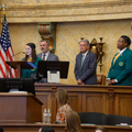 A teenager speaks at a podium as two adults and another teen look on.
