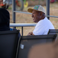 A seated man wearing a baseball hat and smiling.