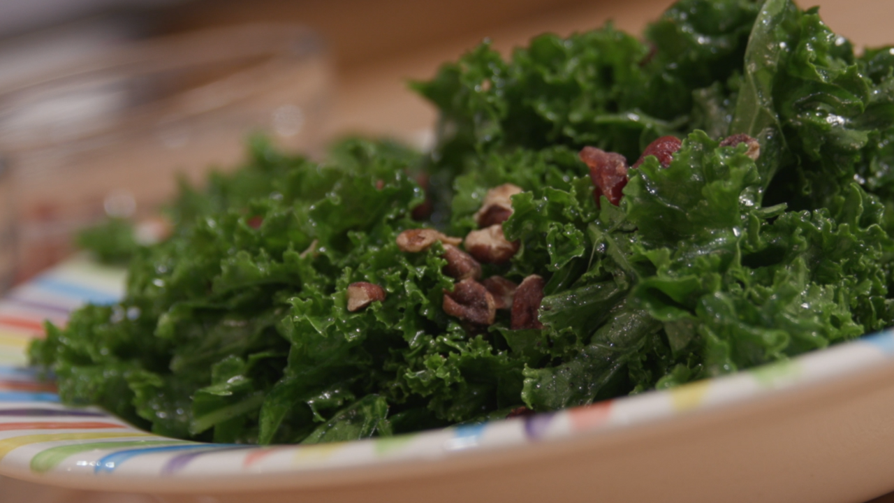 Kale topped with pecans and dried cranberries in a colorful bowl. 