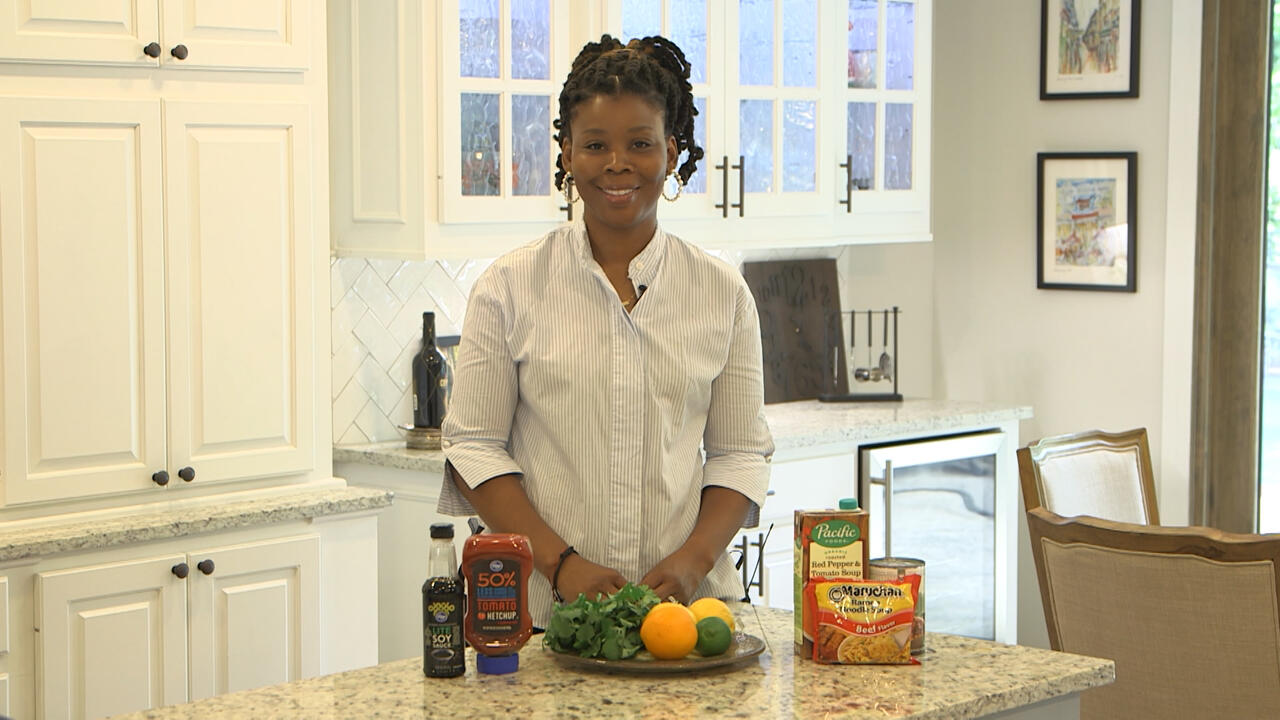 A woman stands behind a kitchen counter.