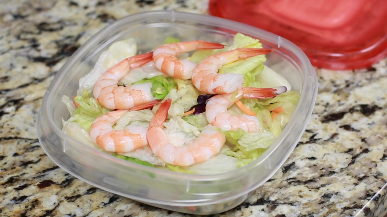 A bowl of salad with shrimp on top. 