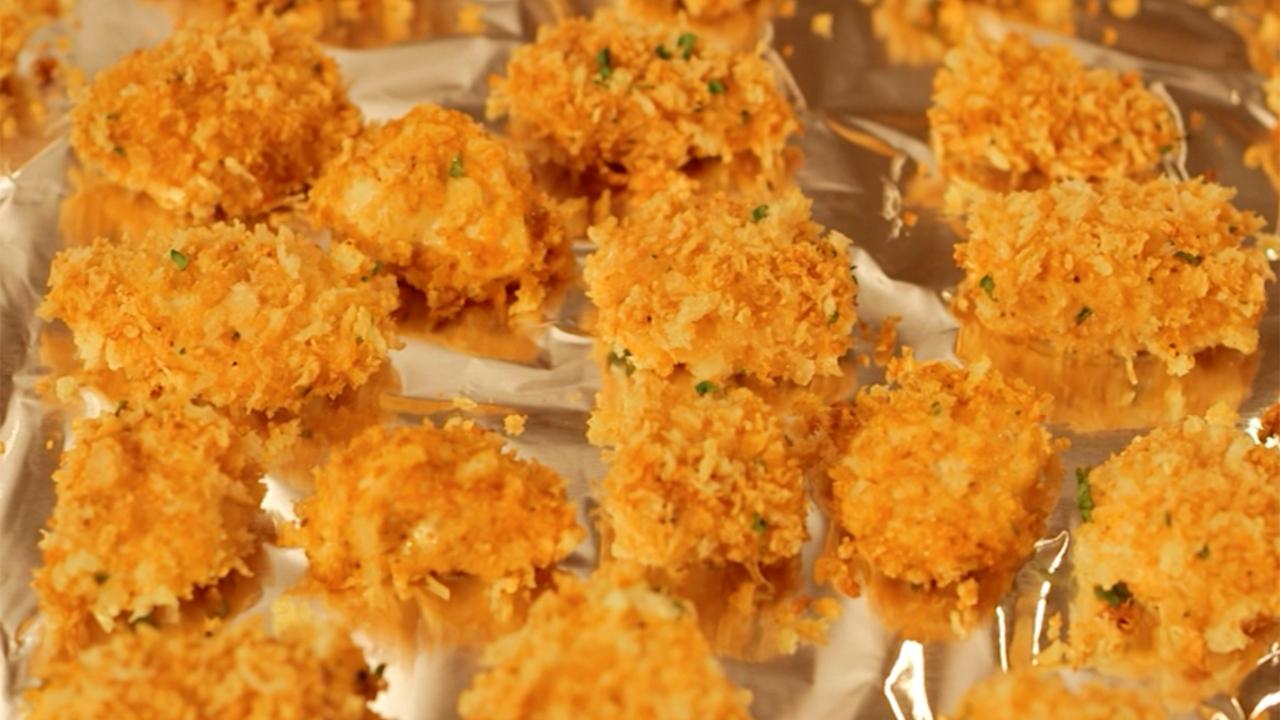 Chicken nuggets coated in golden brown panko breadcrumbs on an aluminum-foil lined baking sheet. 