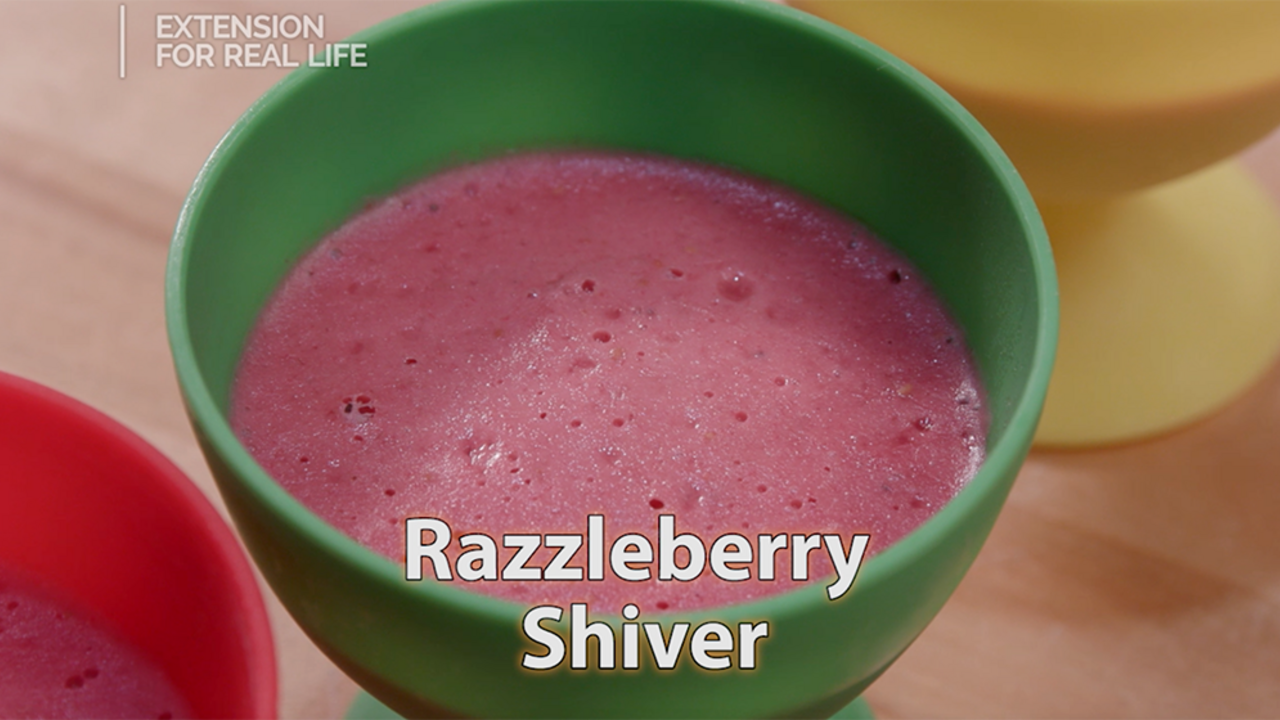 A pink blended raspberry dessert in a green cup.