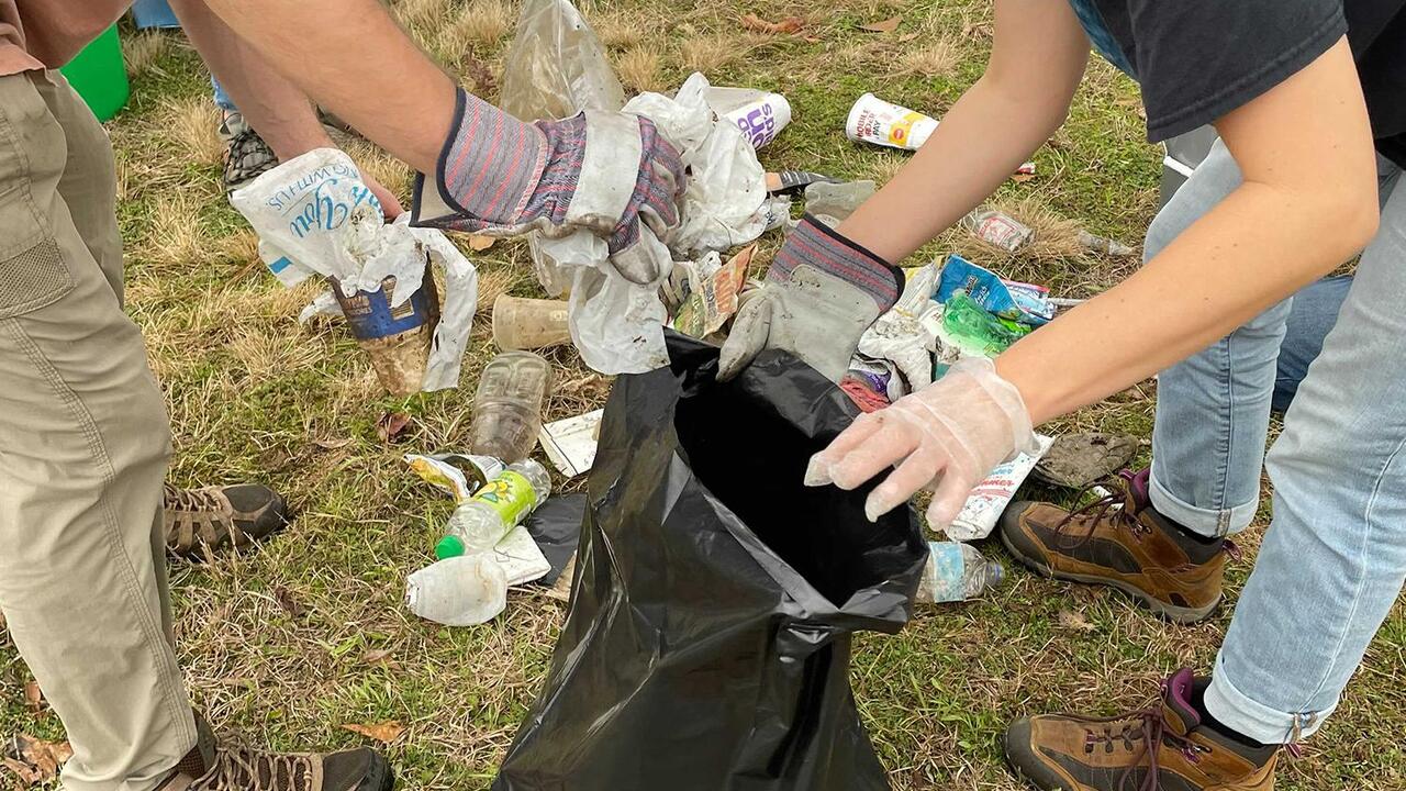 People put trash into a trash bag.