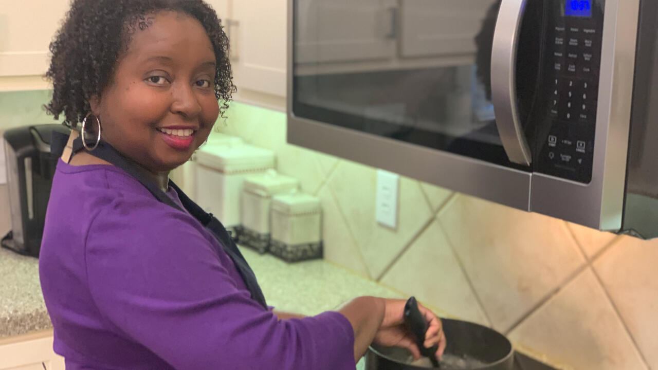 A woman stirs a pot of soup.