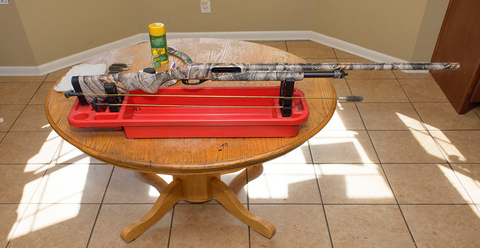 A standard hunting rifle is displayed on a coffee table in preparation for cleaning.