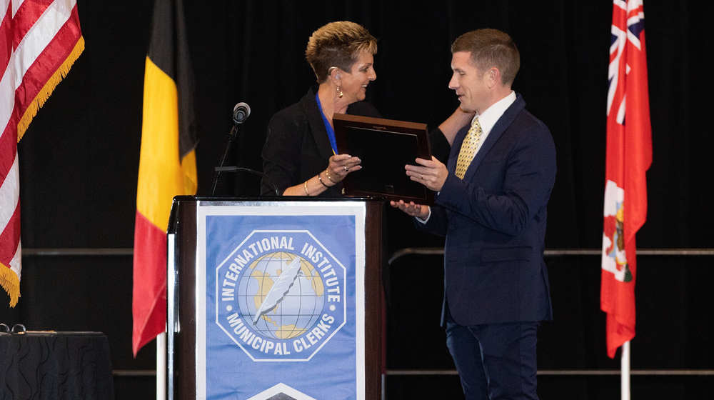  A person accepts a plaque from another person.